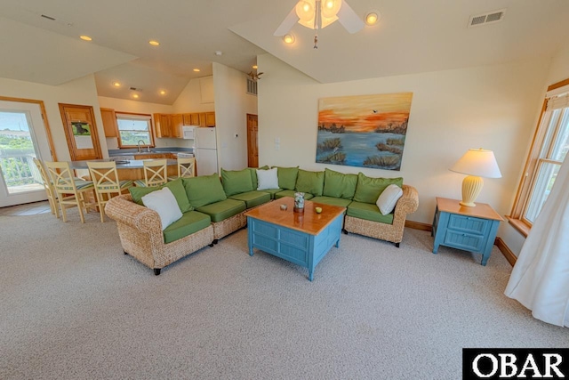 living area with lofted ceiling, plenty of natural light, light carpet, and visible vents