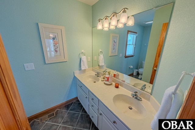 bathroom featuring toilet, a sink, visible vents, and tile patterned floors