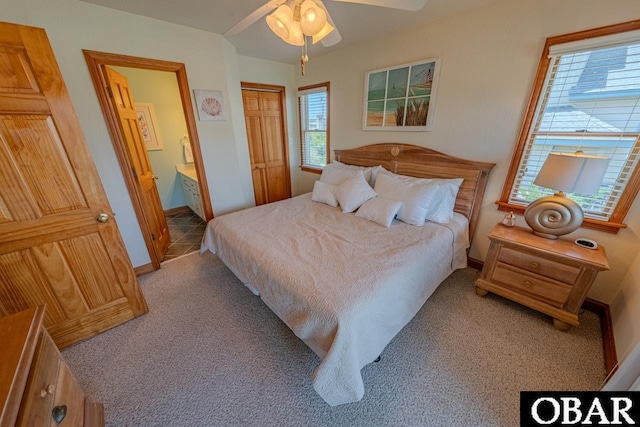 carpeted bedroom with a closet, ceiling fan, baseboards, and ensuite bathroom