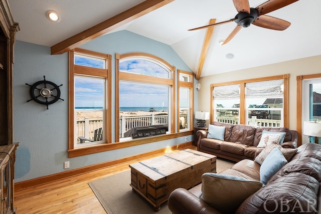 living area with lofted ceiling, light wood finished floors, baseboards, and a ceiling fan