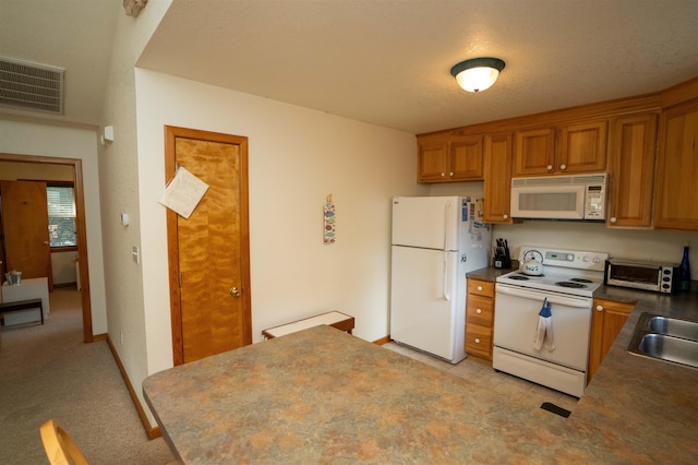 kitchen with white appliances, visible vents, brown cabinetry, dark countertops, and a sink