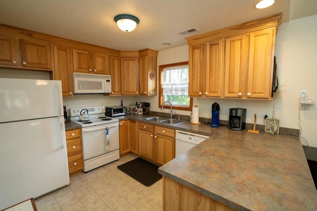 kitchen with dark countertops, visible vents, brown cabinetry, a sink, and white appliances