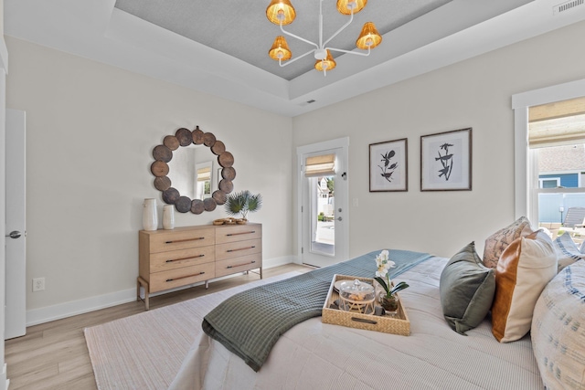 bedroom with access to outside, baseboards, a raised ceiling, and wood finished floors