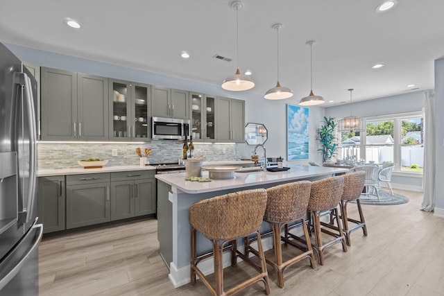 kitchen featuring visible vents, light countertops, appliances with stainless steel finishes, hanging light fixtures, and decorative backsplash