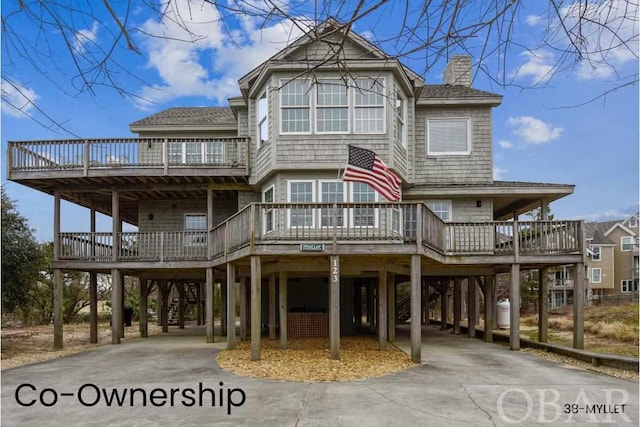 view of front facade with a carport, driveway, a chimney, and a wooden deck