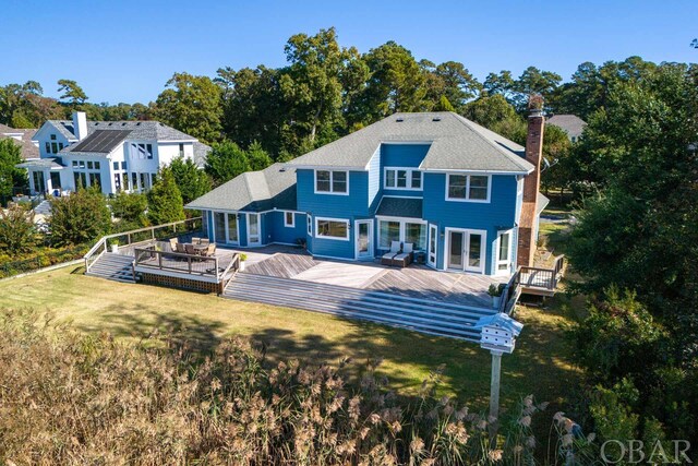 back of property with french doors, a lawn, a chimney, and a wooden deck