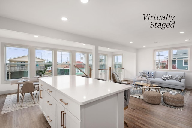 kitchen with a center island, light countertops, light wood-style floors, open floor plan, and white cabinets