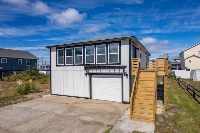 exterior space with a garage, concrete driveway, stairway, and board and batten siding