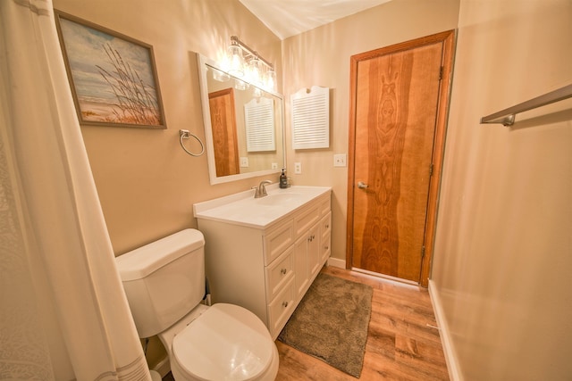 bathroom with toilet, wood finished floors, vanity, and baseboards