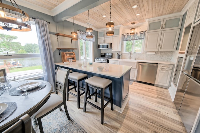 kitchen featuring glass insert cabinets, a center island, light countertops, and appliances with stainless steel finishes