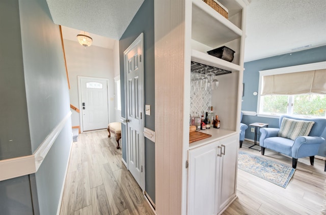 corridor featuring light wood-style flooring and a textured ceiling