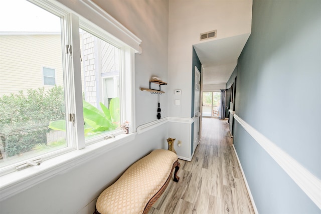 corridor with light wood-type flooring, baseboards, and visible vents