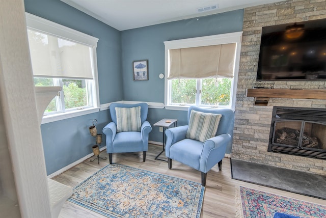 living area with a healthy amount of sunlight, light wood-type flooring, visible vents, and baseboards