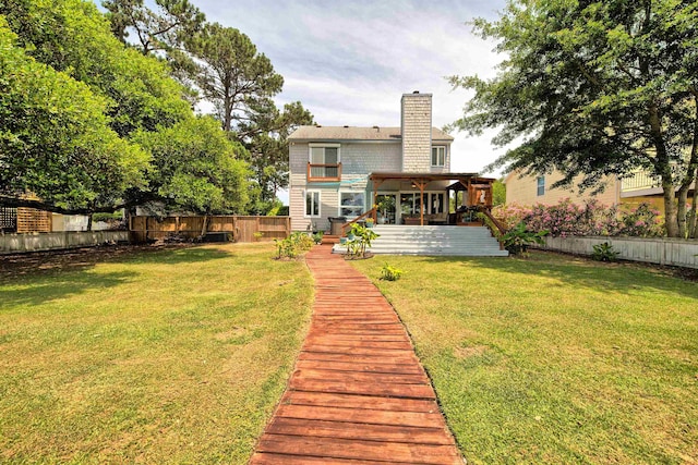 back of house with a fenced backyard, a chimney, a deck, and a yard