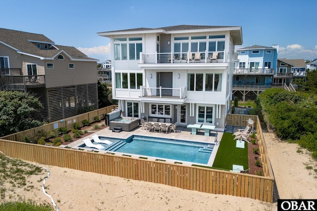 back of house featuring a patio, a fenced backyard, a balcony, an outdoor hot tub, and a fenced in pool