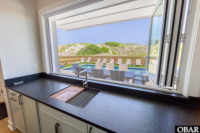 kitchen with dark countertops, a sink, and a healthy amount of sunlight