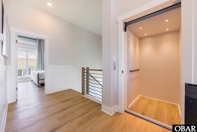 hall featuring light wood-style flooring, recessed lighting, an upstairs landing, and elevator