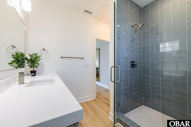 full bathroom featuring visible vents, a tile shower, vanity, and wood finished floors