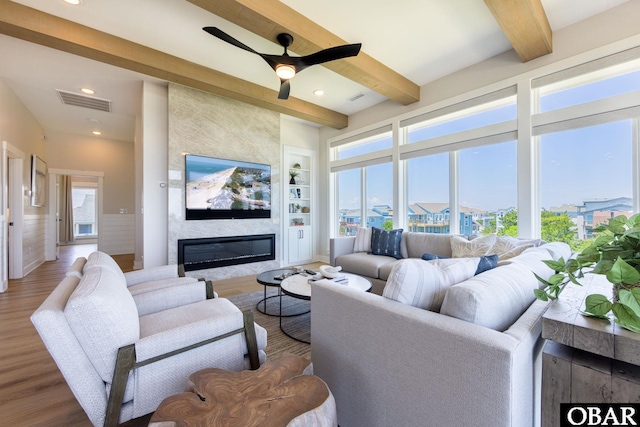 living area featuring built in features, plenty of natural light, beam ceiling, and a fireplace