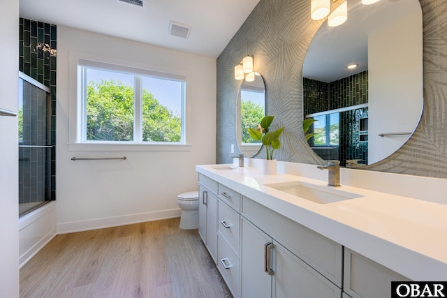 bathroom featuring toilet, wood finished floors, visible vents, a sink, and baseboards