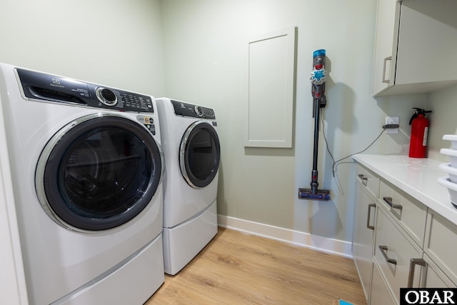 laundry area with cabinet space, light wood-style flooring, baseboards, and separate washer and dryer