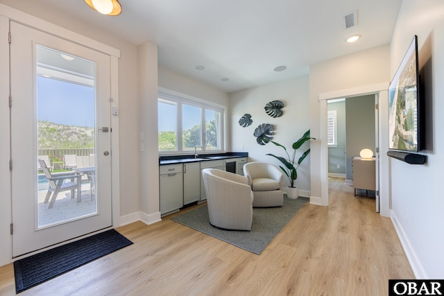 interior space with visible vents, baseboards, light wood-style floors, a sink, and recessed lighting