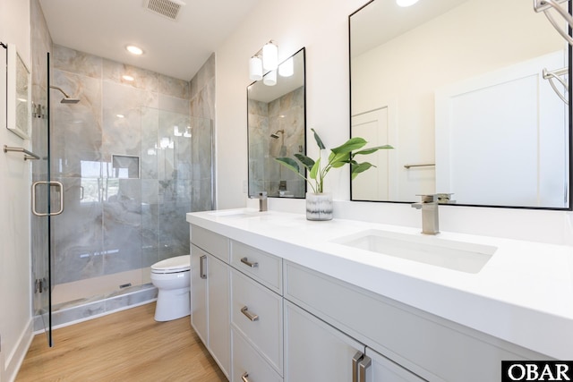 full bath featuring a stall shower, visible vents, toilet, wood finished floors, and a sink