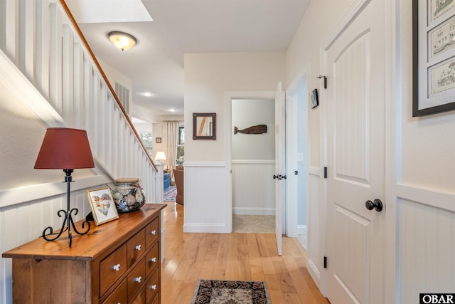 entrance foyer with a wainscoted wall, stairway, and light wood-style floors