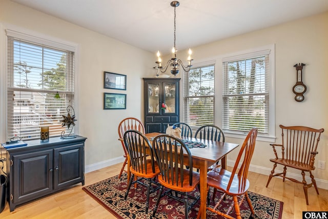 dining room with light wood-style floors, baseboards, and a notable chandelier