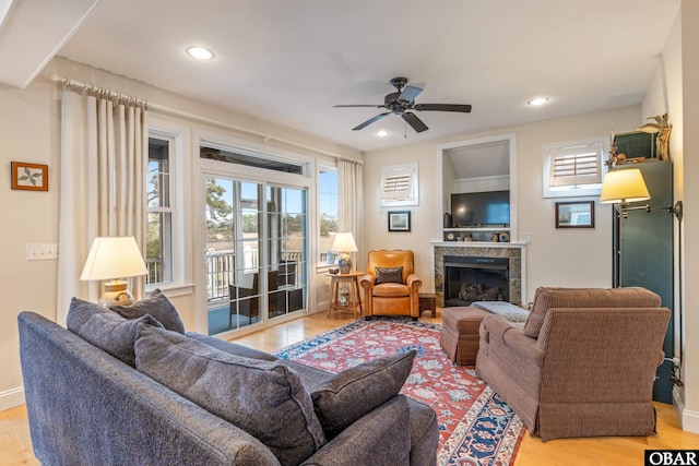 living room featuring a tiled fireplace, light wood finished floors, and plenty of natural light