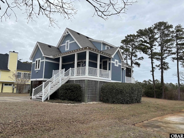 view of front facade with stairway, roof with shingles, covered porch, a front lawn, and board and batten siding