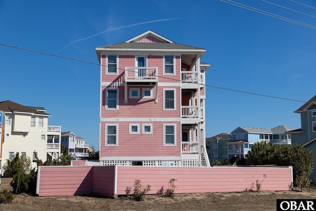 view of front of property featuring a balcony, a residential view, and fence