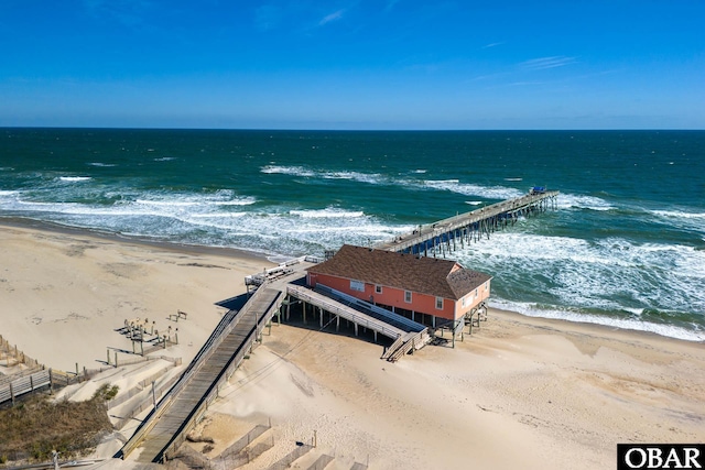 bird's eye view featuring a pier, a water view, and a beach view