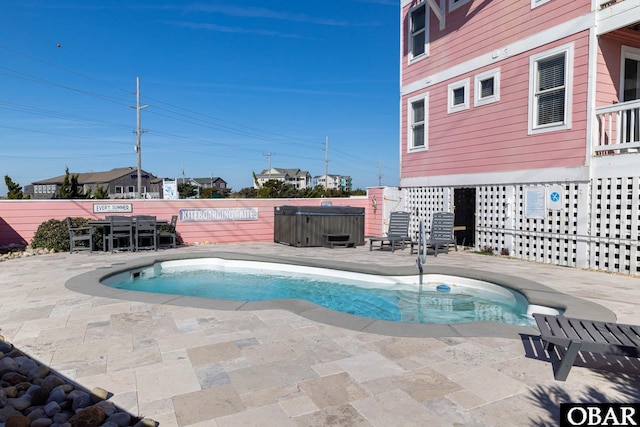 view of swimming pool with fence, a covered hot tub, and a patio