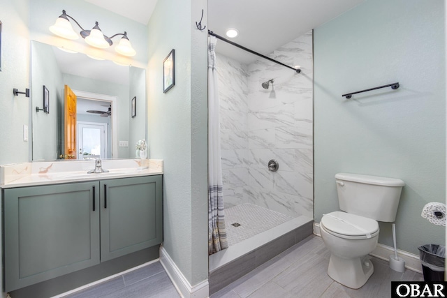 bathroom with toilet, wood tiled floor, a shower stall, vanity, and baseboards