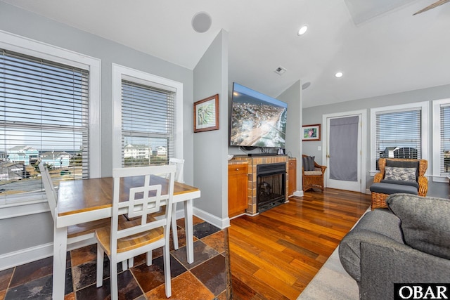 living area featuring vaulted ceiling, baseboards, a fireplace, and dark wood-style flooring