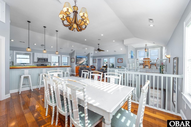 dining area featuring a chandelier, lofted ceiling, a healthy amount of sunlight, and wood finished floors