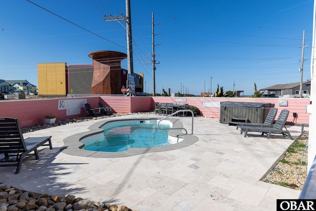 view of swimming pool with a patio area, fence, a pool, and a hot tub