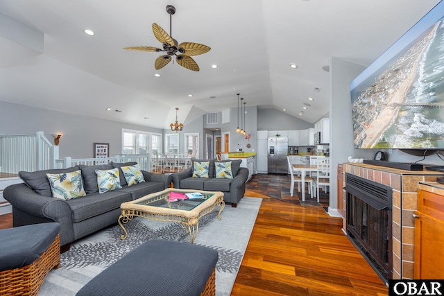 living area with recessed lighting, ceiling fan with notable chandelier, a fireplace, wood finished floors, and vaulted ceiling