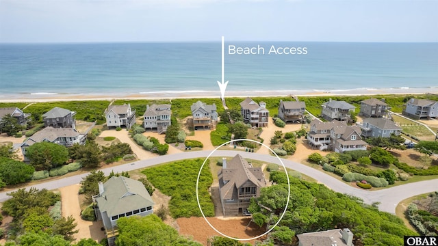 drone / aerial view featuring a water view, a beach view, and a residential view
