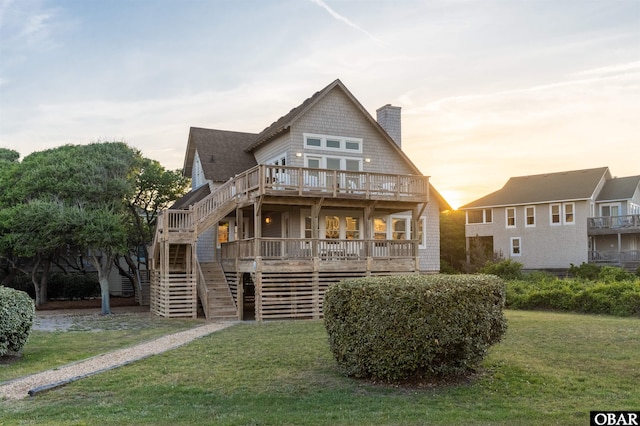view of front of home with a wooden deck, a chimney, a front yard, and stairs