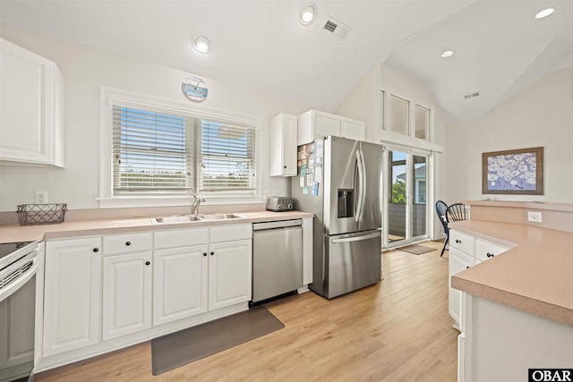 kitchen with stainless steel appliances, a sink, lofted ceiling, plenty of natural light, and white cabinets