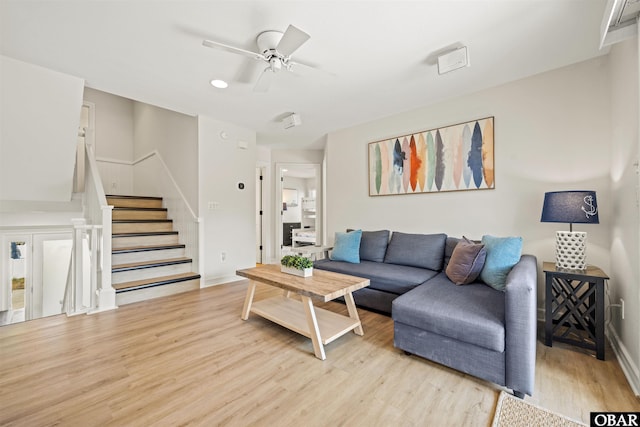 living room with light wood-style flooring, ceiling fan, stairs, baseboards, and recessed lighting