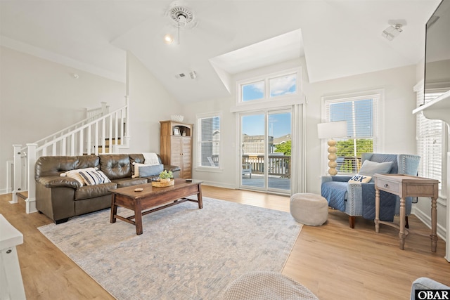 living room featuring high vaulted ceiling, light wood finished floors, and baseboards
