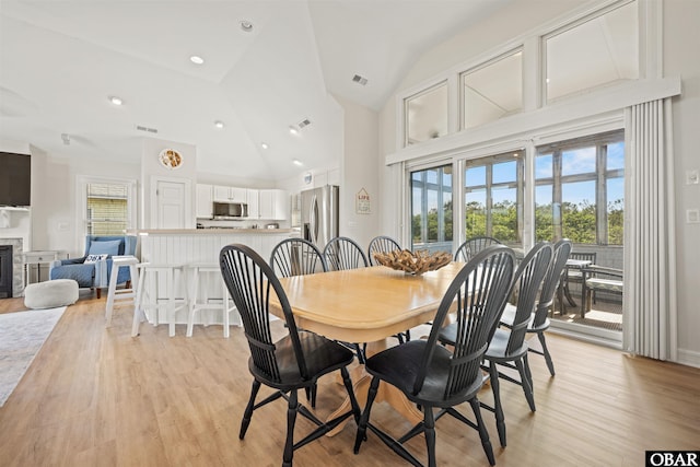 dining room featuring light wood-type flooring and high vaulted ceiling