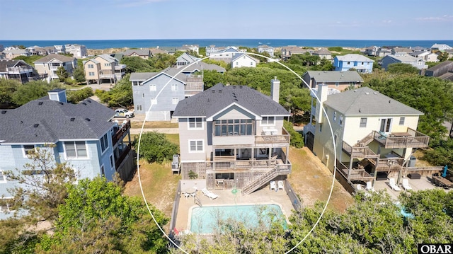 aerial perspective of suburban area featuring a pool area and a nearby body of water