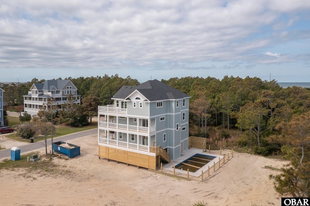 rear view of house featuring a view of trees and a balcony