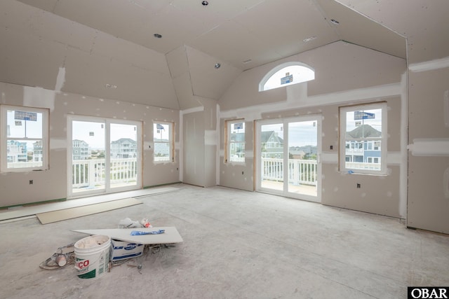 unfurnished living room featuring high vaulted ceiling and a healthy amount of sunlight