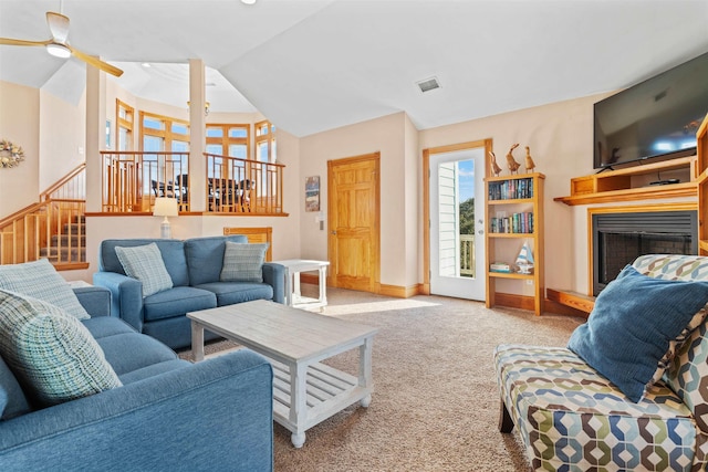 carpeted living area featuring visible vents, baseboards, a fireplace with raised hearth, a ceiling fan, and vaulted ceiling