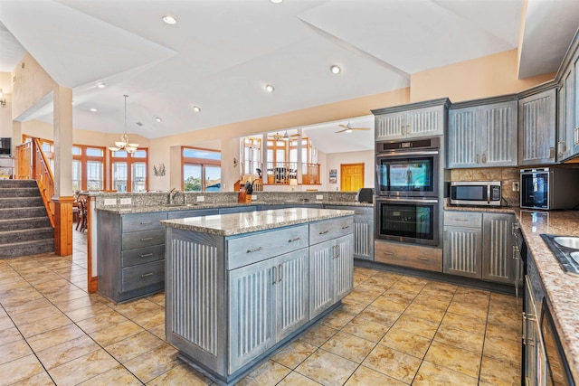 kitchen with a peninsula, appliances with stainless steel finishes, a sink, and gray cabinetry